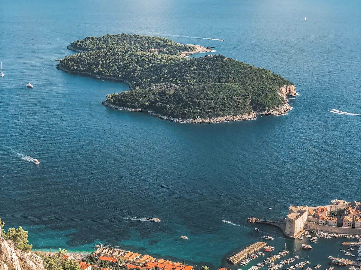 High angle view from Mount Srđ showing the full shape of Lokrum Island with the Old Town port visible in the corner to highlight the short distance