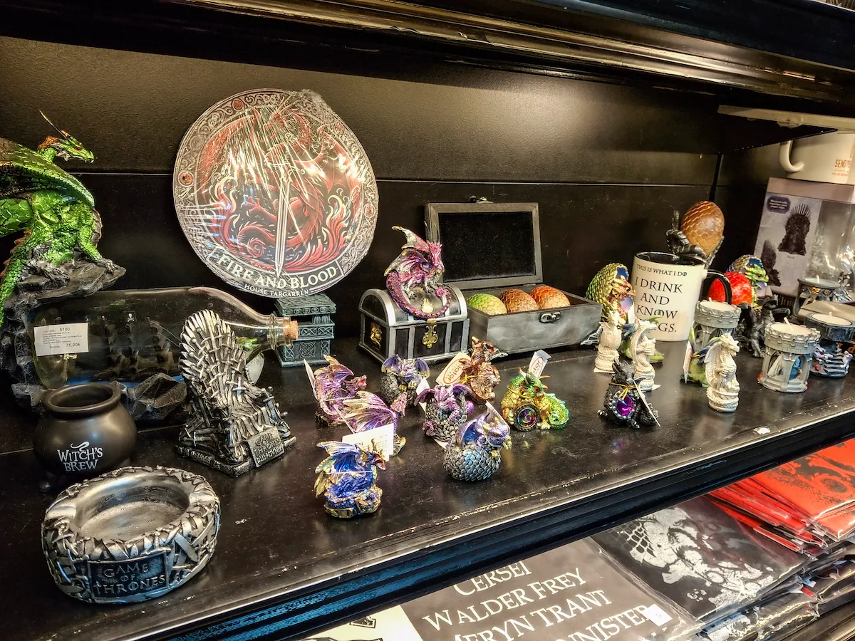 Display shelves in a Dubrovnik souvenir shop featuring an assortment of fantasy-themed figurines, dragon eggs, and mugs