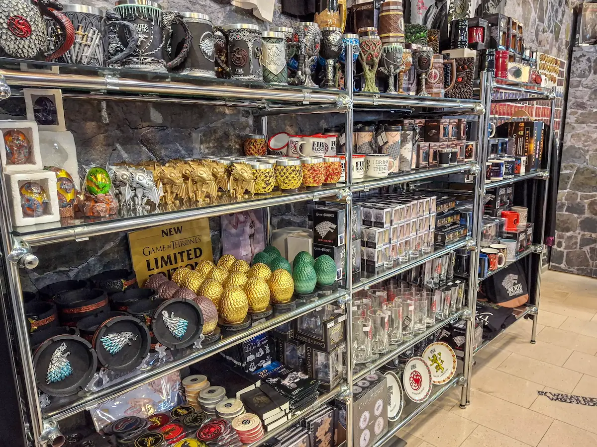 Souvenir display shelves at House of Game filled with collectible mugs, dragon eggs, and souvenirs