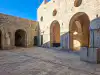 Ground-level courtyard of Fort Lovrijenac featuring a stone well and the door of St. Lawrence Chapel