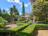 View looking across the central courtyard garden toward the historic ruined walls of the Benedictine monastery on Lokrum Island