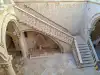 Angled down view from the upper gallery looking at the main stone staircase inside the Rector's Palace