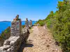 Lower Trsteno rocky coastal platform featuring three square stone pillars with vases and distant Šipan island