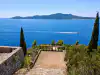 Dirt path leading to Trsteno rocky terrace with speedboat in the view across the sea